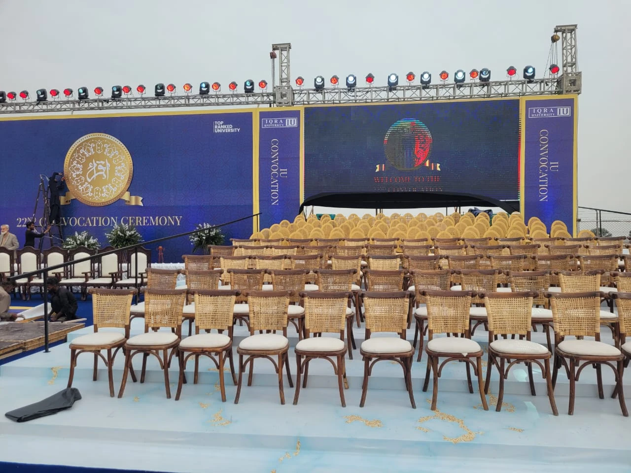 Seating and floral arrangements in front of an outdoor ceremony stage.