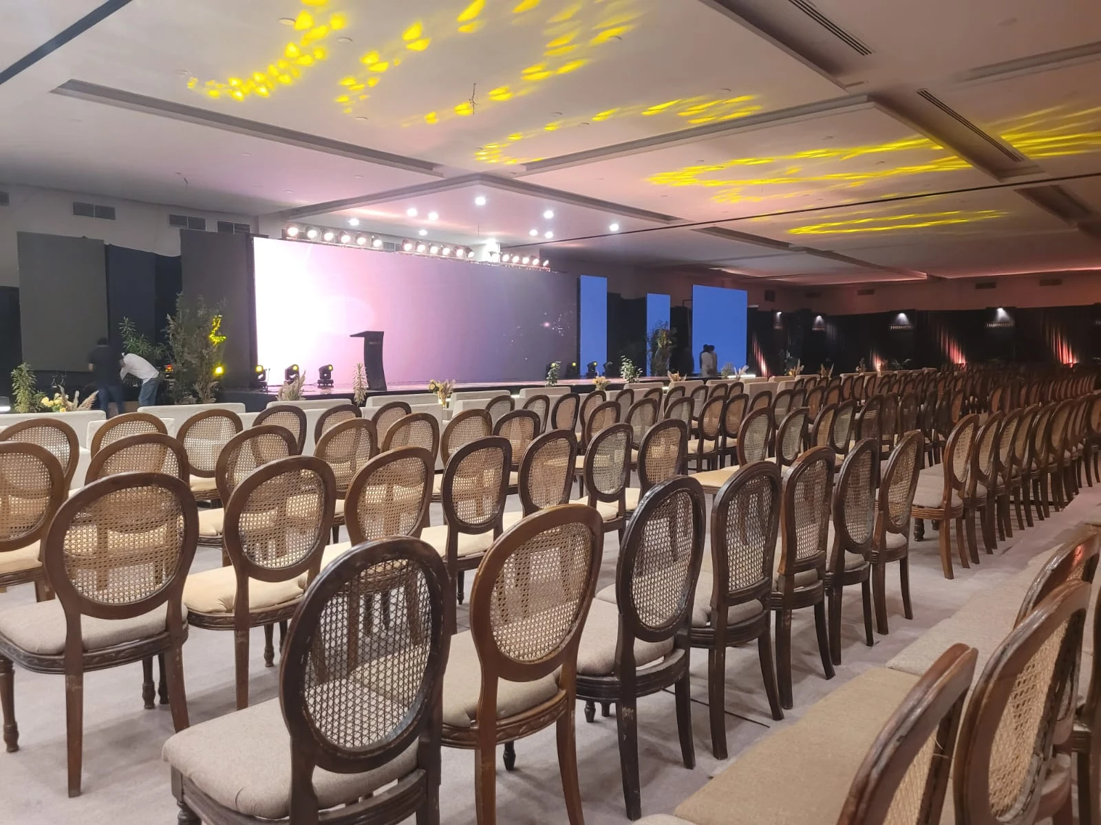 An indoor venue prepared with rows of seating and a lit stage.