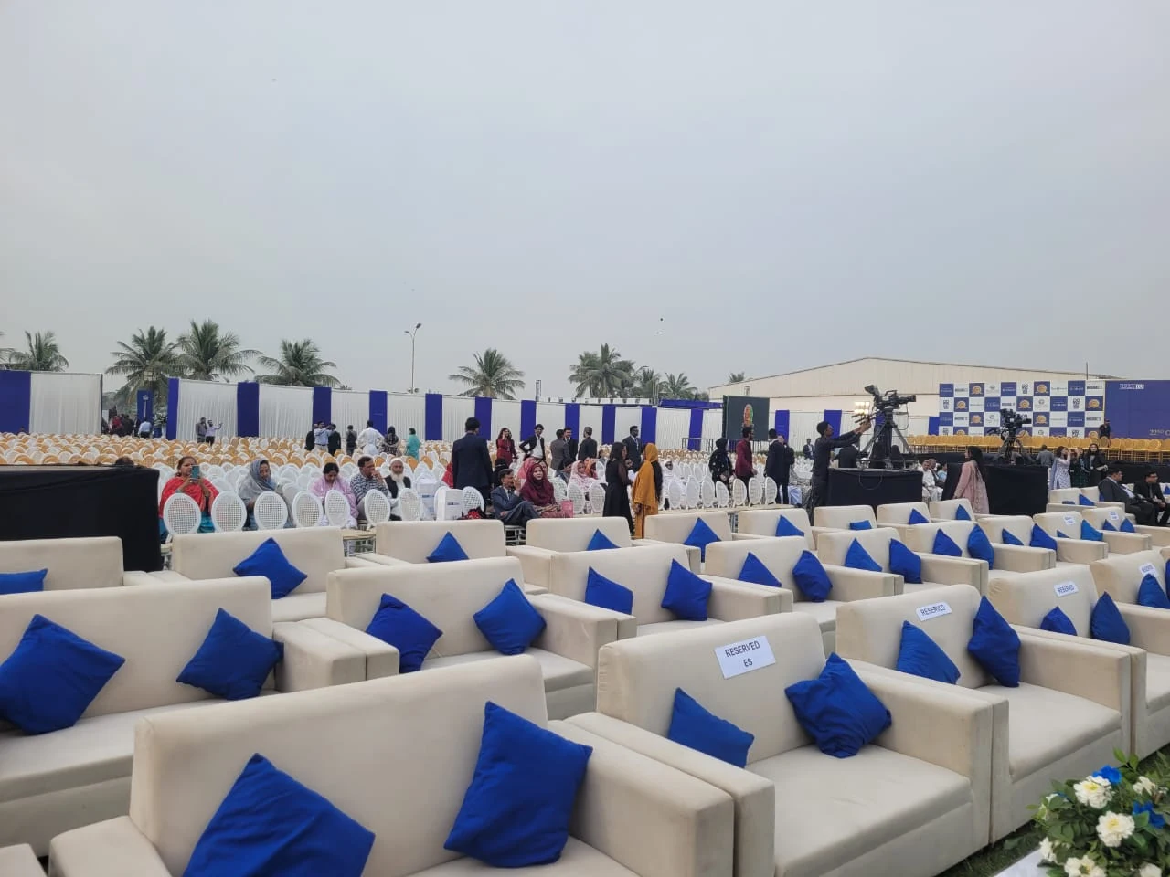 White lounge seating with blue cushions at an outdoor gathering.